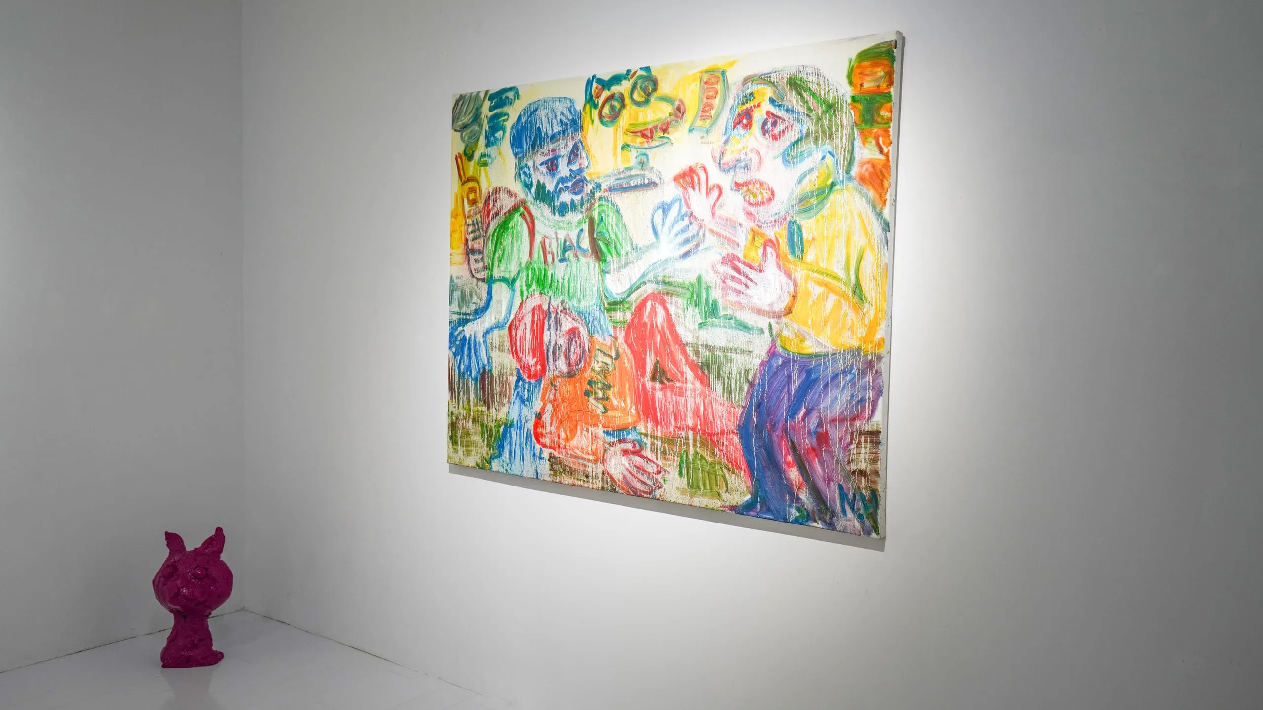 A large multi-figure canvas on a white wall with a magenta cat sculpture crouched on the floor in the corner.
