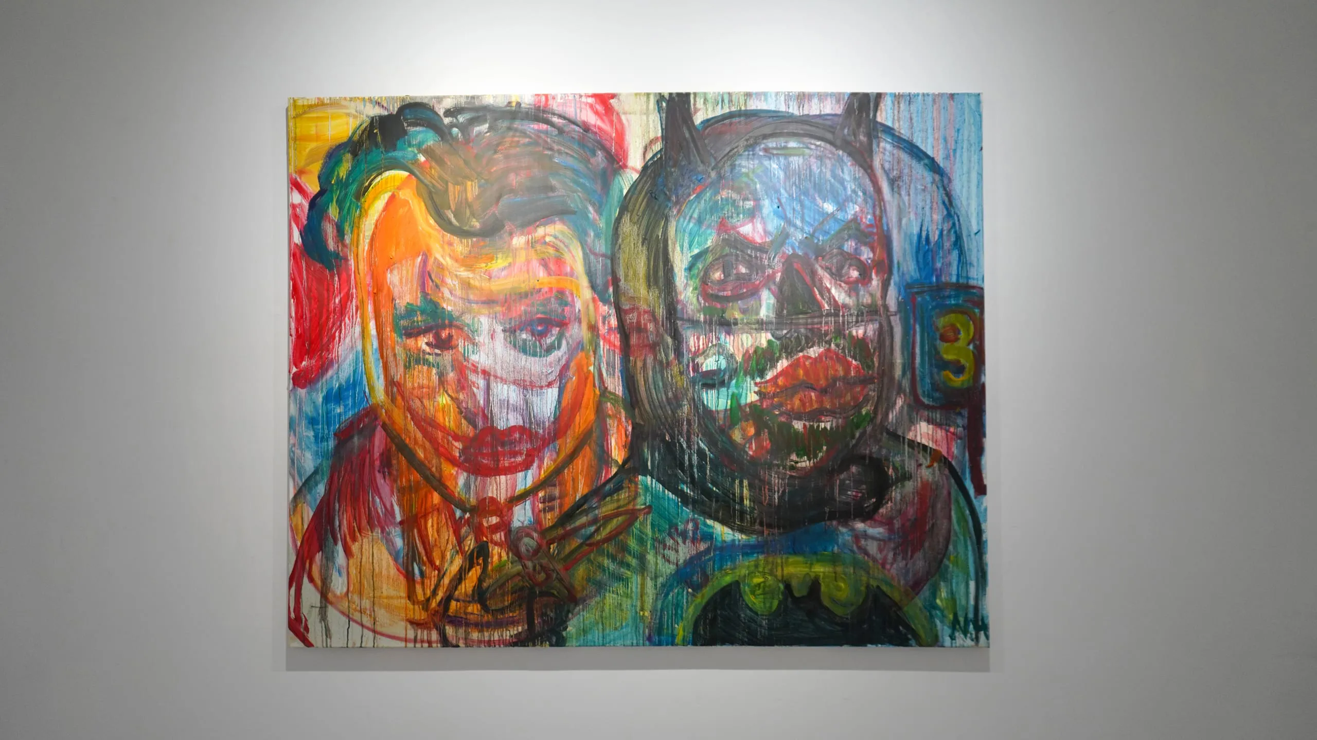 Two faces side by side — one painted in hot reds and oranges, the other sunk into bruised blue-black over a bat emblem.