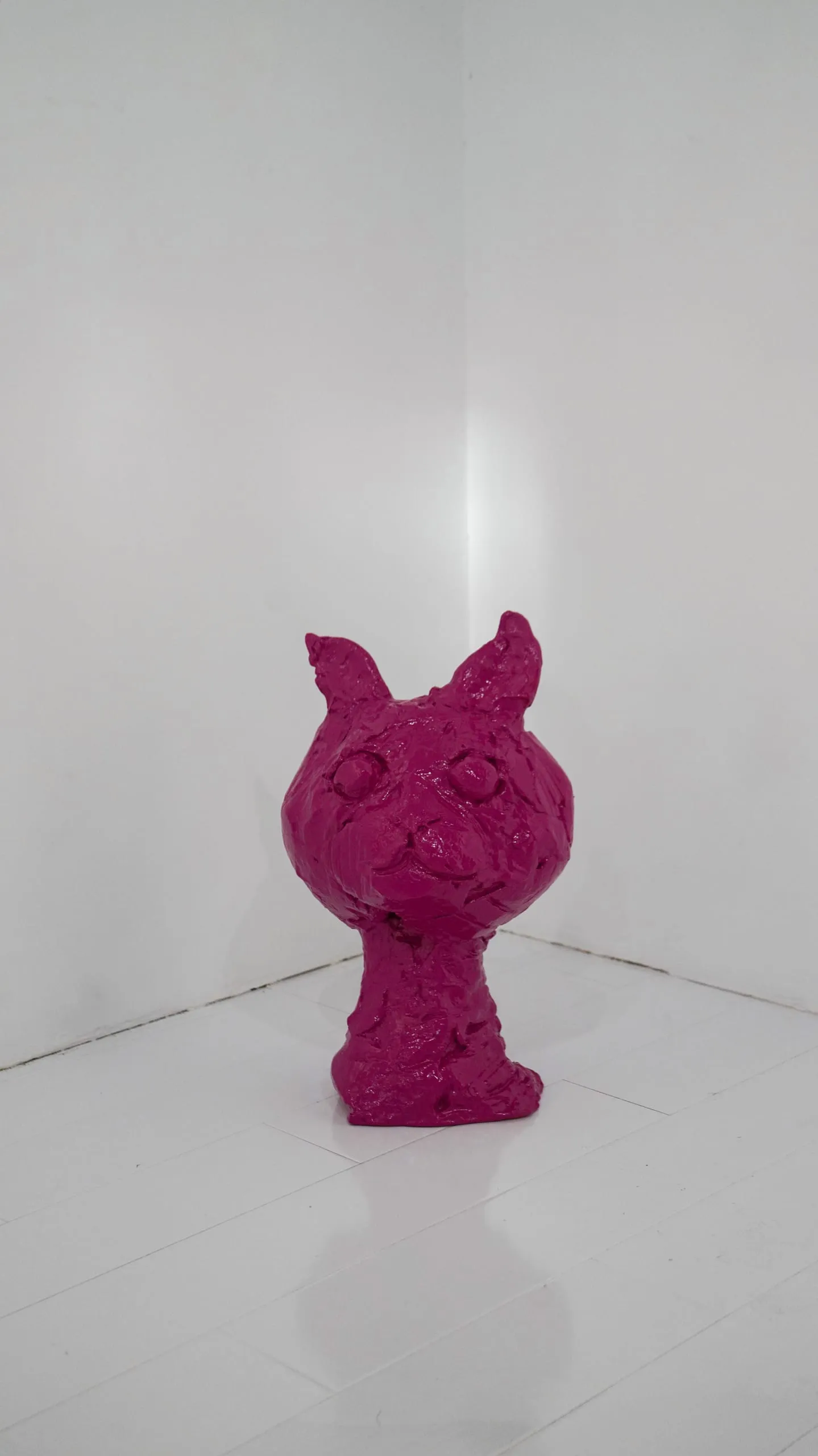 A roughly modelled magenta cat sculpture in the corner of the gallery.
